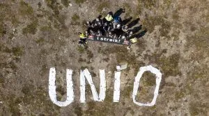 En gruppe mennesker foran teksten "Unio". Foto.